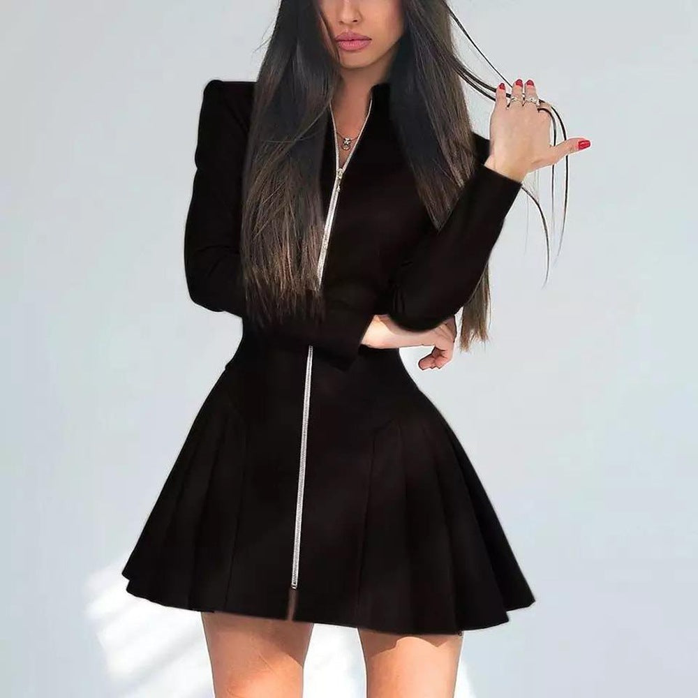 Woman wearing a black leather-like dress with a pleated skirt and long sleeves, with a zipper closure