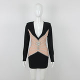 Mannequin displaying a black mini dress with a deep V-neck, sheer paneling, and silver embellishments.