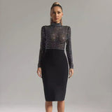 Full-length shot of a woman in a black long-sleeved mock neck dress with sheer rhinestone-embellished top and black pencil skirt.