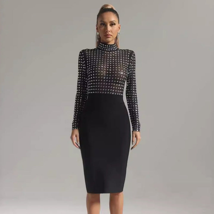 Full-length shot of a woman in a black long-sleeved mock neck dress with sheer rhinestone-embellished top and black pencil skirt.
