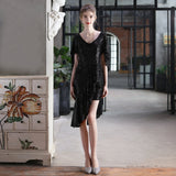 Woman in a black sequined dress with an asymmetrical hemline and flutter sleeves