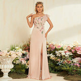 A woman in a pink one-shoulder gown with floral embroidery and a high slit