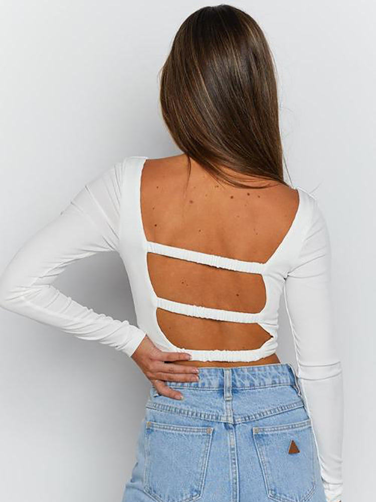 Back view of a woman wearing a white long-sleeved crop top with an open back