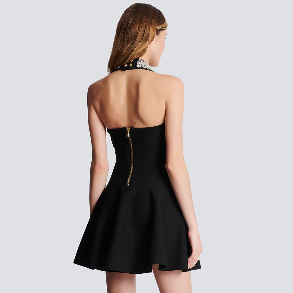 Back view of a woman in a black halter dress with a jeweled neckline and large button details.