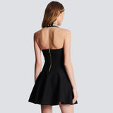 Back view of a woman in a black halter dress with a jeweled neckline and large button details.