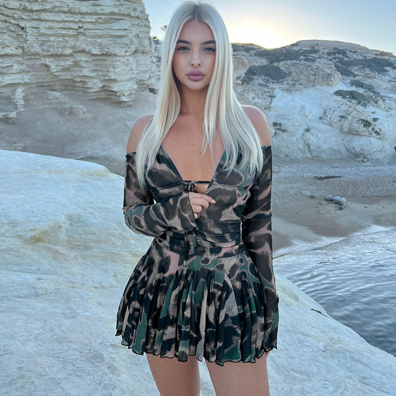woman in a short dress with a camouflage print standing on rocks by the sea