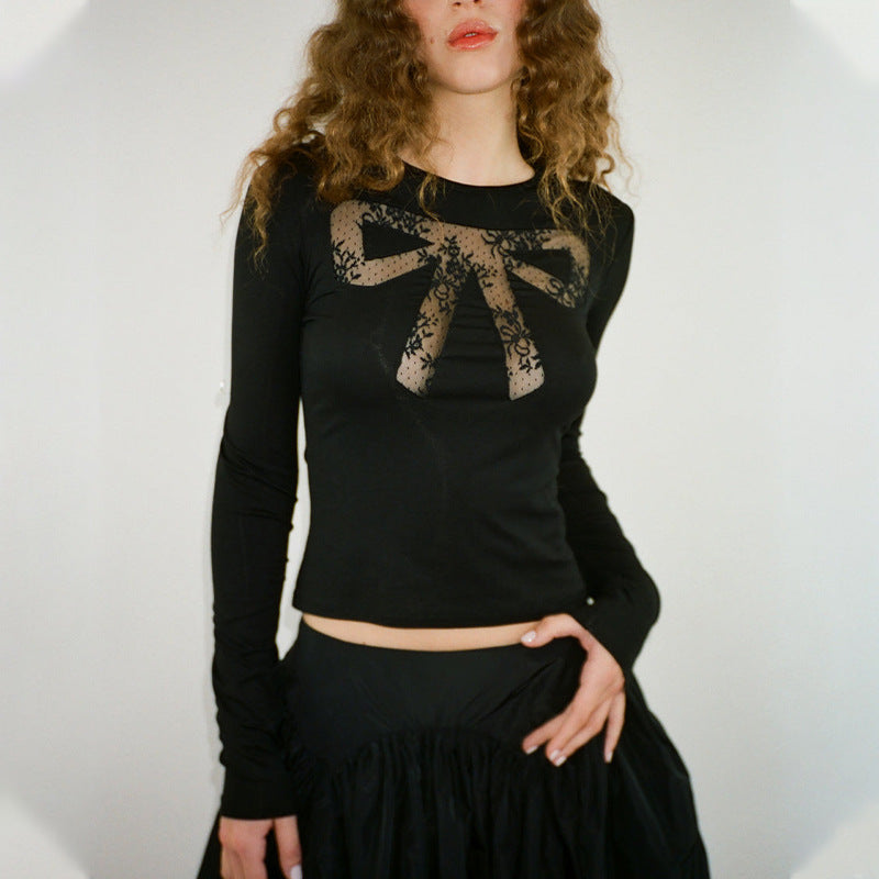 A woman wears a black long-sleeved shirt with a lace bow design on the chest and a black ruffled skirt.