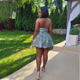 A woman in a green halter dress walks away from the camera in a backyard.