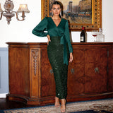 A woman poses in a dark green satin wrap top and sequined skirt.
