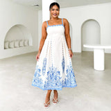 Woman in a white and blue floral midi dress with scalloped trim and white sandals
