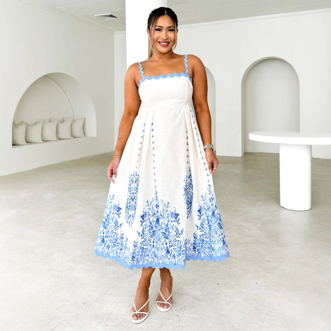 Woman in a white and blue floral midi dress with scalloped trim and white sandals