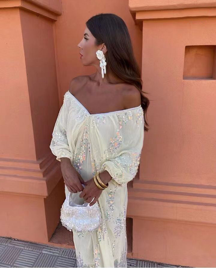 Close-up of a woman in a cream off-the-shoulder maxi dress with sequins.