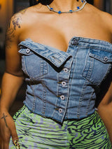 A woman wearing a blue denim strapless corset top with green and purple patterned pants