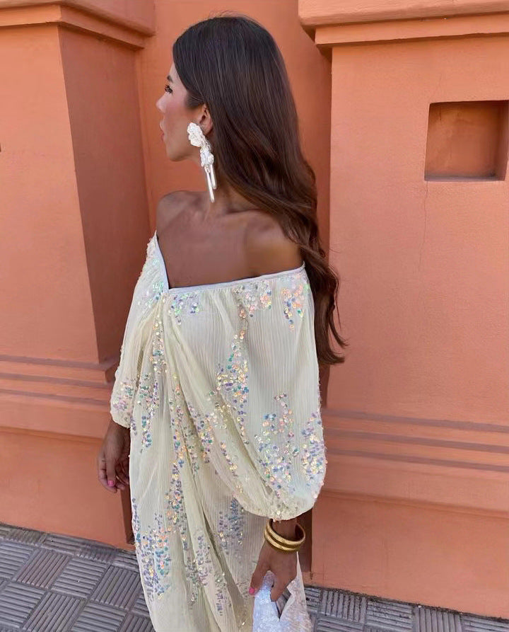 Close-up of a woman in a cream off-the-shoulder maxi dress with sequins, looking to the side.