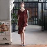 Woman in a burgundy sequined dress with an asymmetrical hemline and flutter sleeves