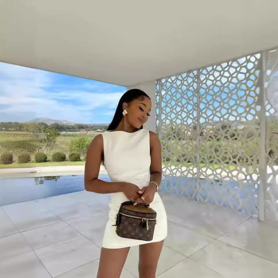 A woman in a white sleeveless mini dress holding a handbag