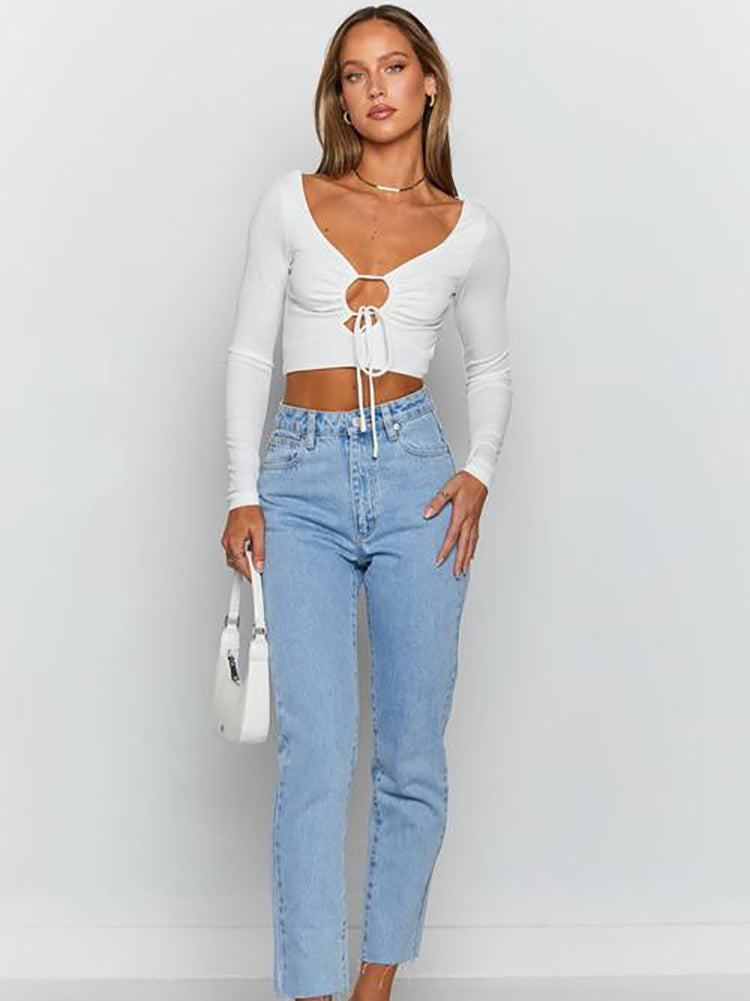 Woman wearing a white long-sleeved crop top and light wash jeans