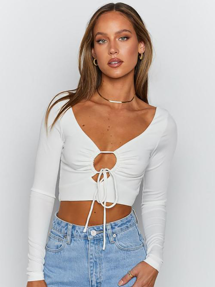Woman wearing a white long-sleeved crop top with a plunging v-neck and tie detail