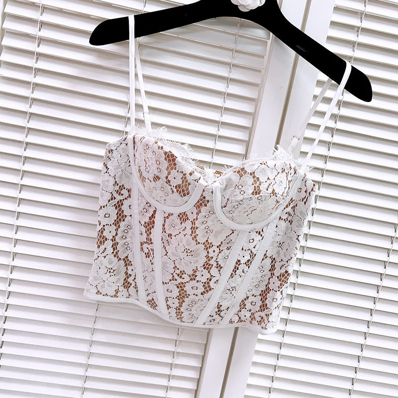 White lace corset top with tan lining, hanging on a black hanger against a white slatted background.