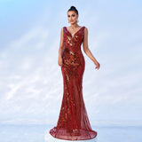 Woman in a red sequined mermaid gown with a v-neck and sleeveless design, posing on a white platform.