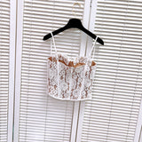 Front view of a white lace corset top with tan lining, detailed lace pattern, and adjustable straps.