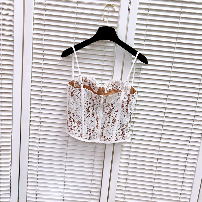 Front view of a white lace corset top with tan lining, detailed lace pattern, and adjustable straps.