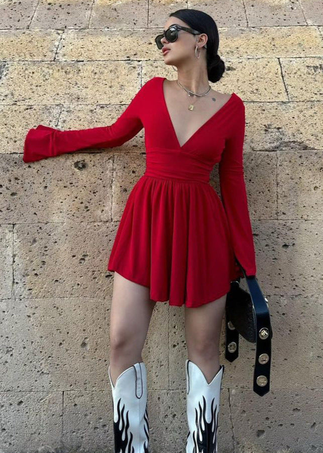 Woman wearing a red mini dress with flared sleeves, a deep V-neck, and cowboy boots.