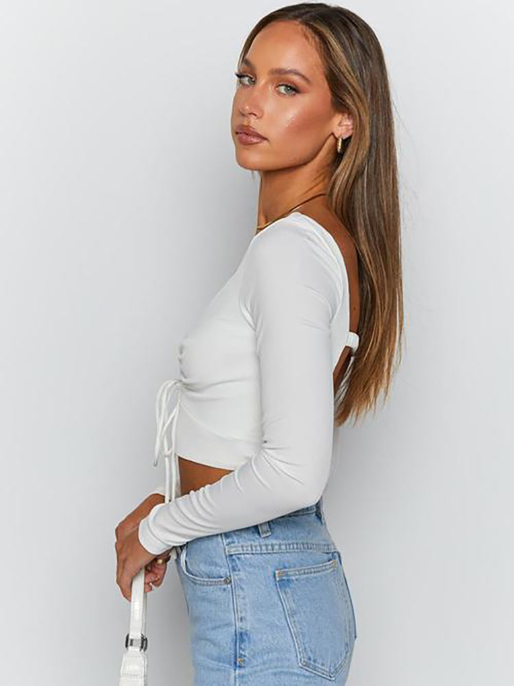 Side view of a woman wearing a white long-sleeved crop top and light wash jeans