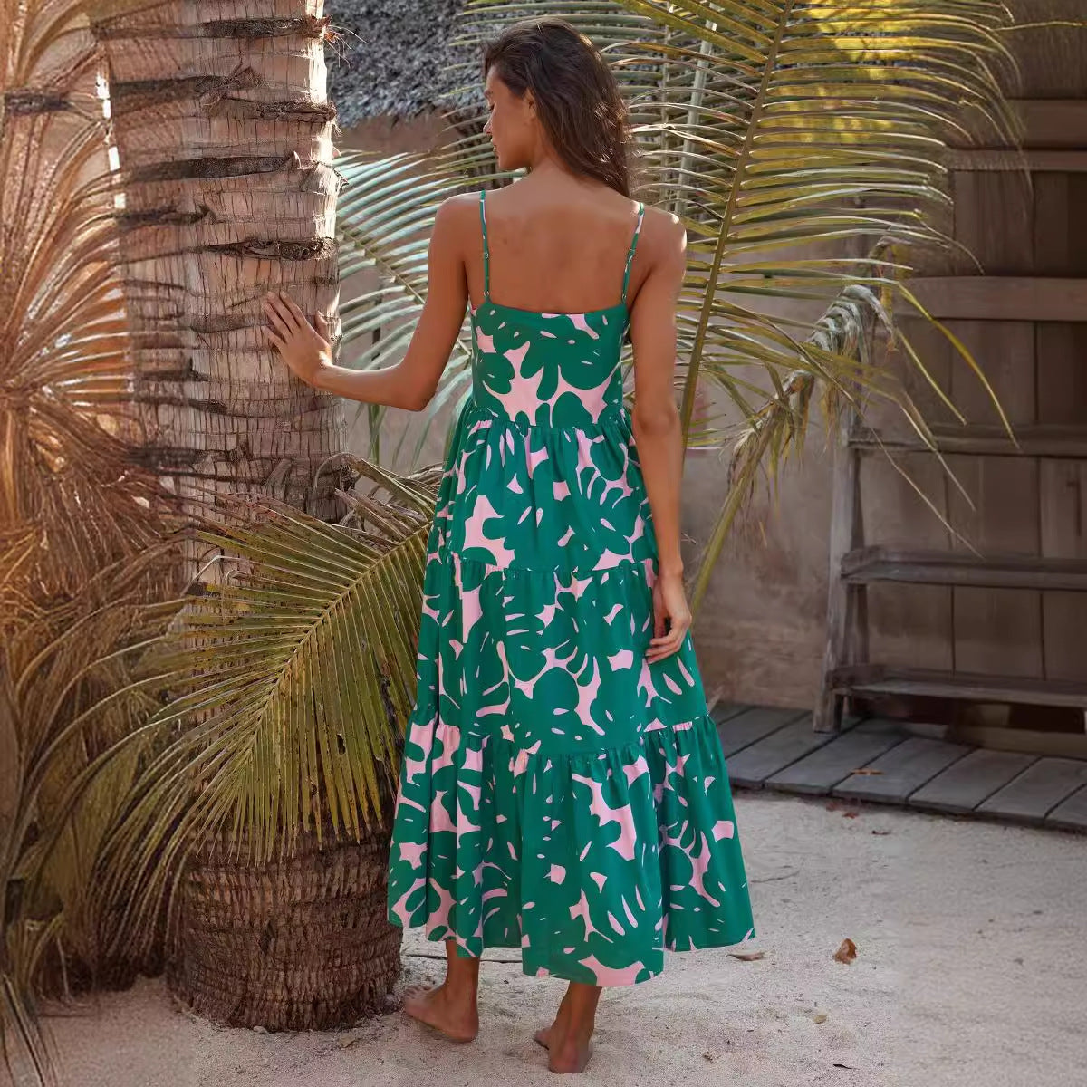 woman wearing a green and pink leaf print tiered midi dress from the back