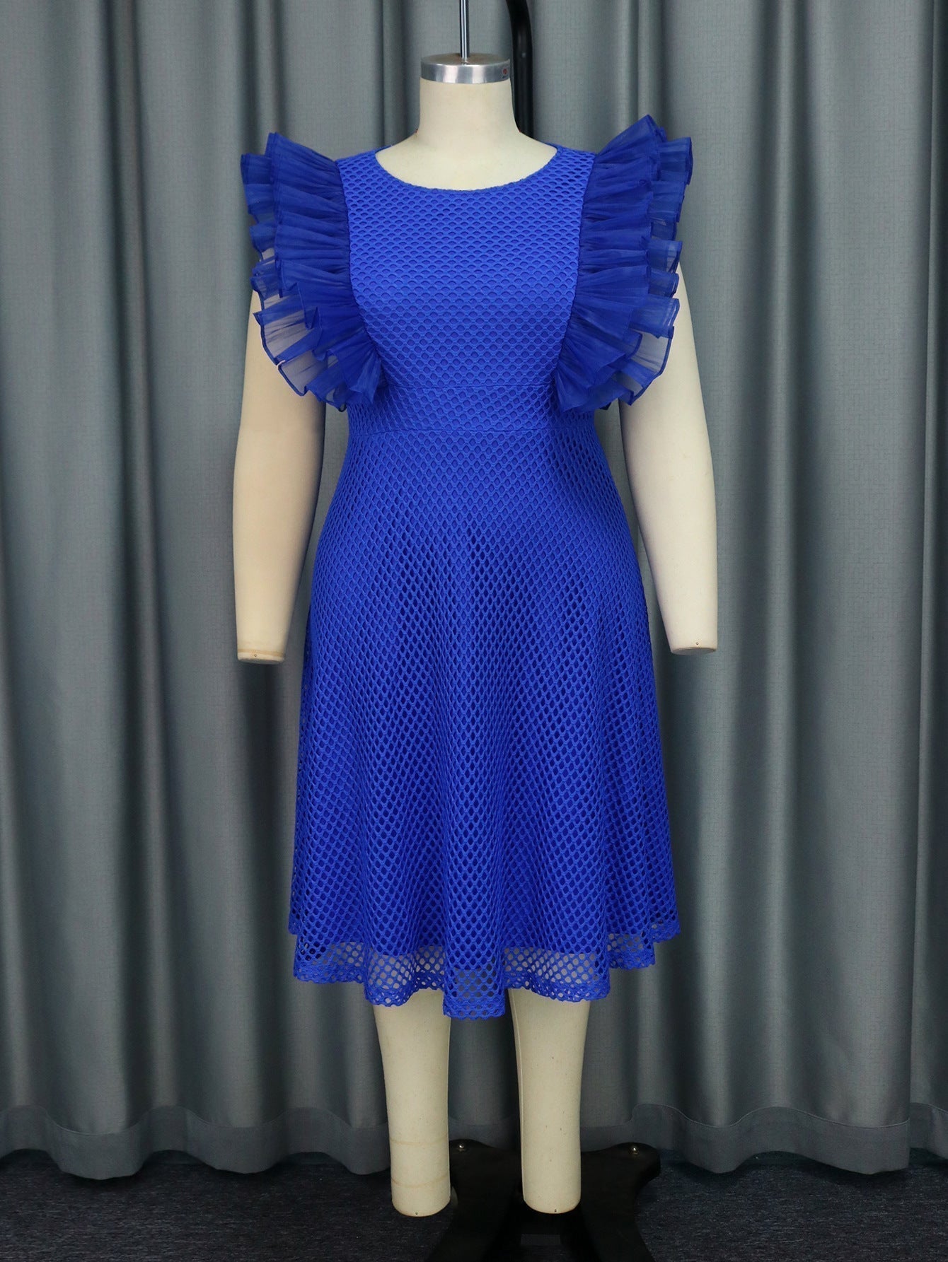 A royal blue dress with ruffled sleeves and a mesh overlay on a mannequin