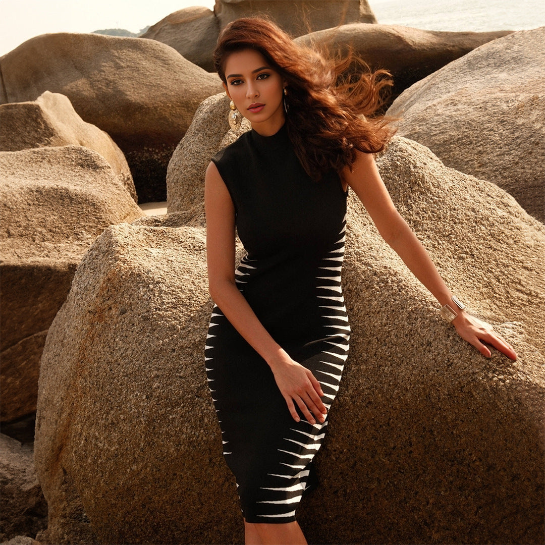 A woman with long, brown hair wears a black mock neck dress with white stripes.