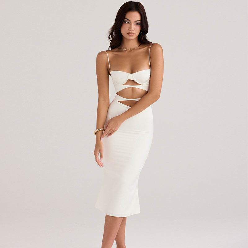A woman wearing a white cut-out midi dress with spaghetti straps and a sweetheart neckline.