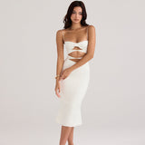 A woman wearing a white cut-out midi dress with spaghetti straps and a sweetheart neckline.