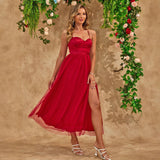 A woman in a red dress with a high slit posing with flowers