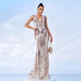 Woman in a champagne and rose gold sequined mermaid gown with a v-neck and sleeveless design, holding a clutch.
