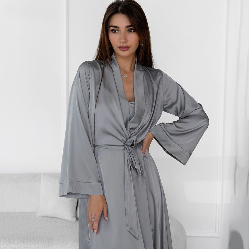 Woman in a grey satin robe tied at the waist, posing with one hand on her hip.