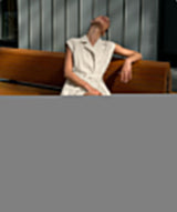A blurry close-up of a woman in an ivory dress sitting on a bench.