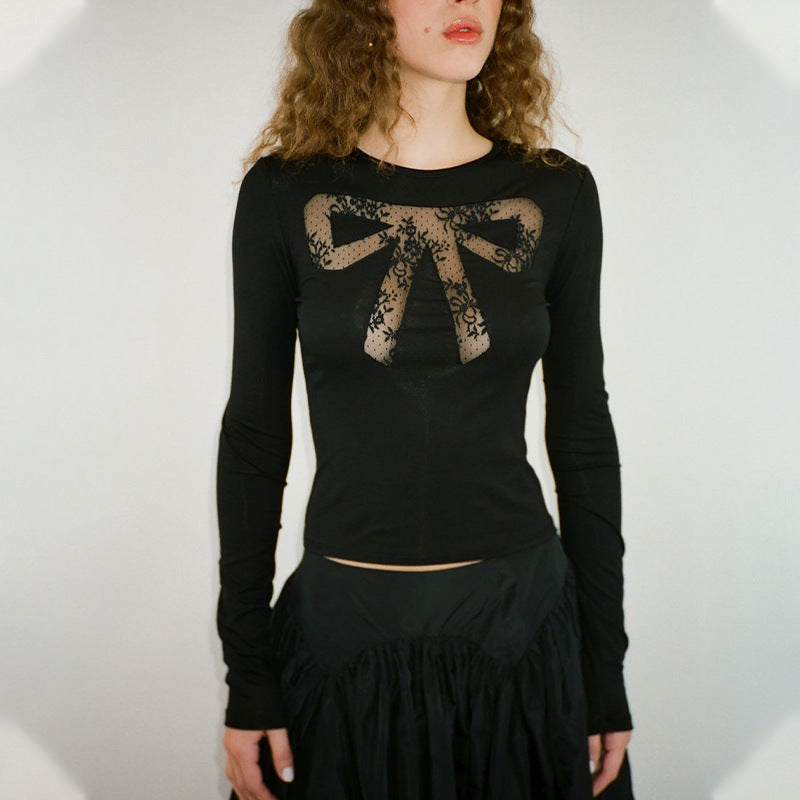 A woman wears a black long-sleeved shirt with a lace bow design on the chest and a black ruffled skirt.
