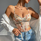 A woman wearing a tie-dye corset top with a white unbuttoned shirt draped over her shoulders.