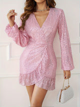 Woman in a pink sequin mini dress with bell sleeves and a ruffle hem, holding a pearl clutch.