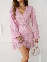 Woman in a pink sequin mini dress with bell sleeves and a ruffle hem, holding a pearl clutch.