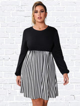 Woman wearing a black and white striped dress with long sleeves and a round neckline.