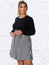 Woman wearing a black and white striped dress, with hands clasped in front.