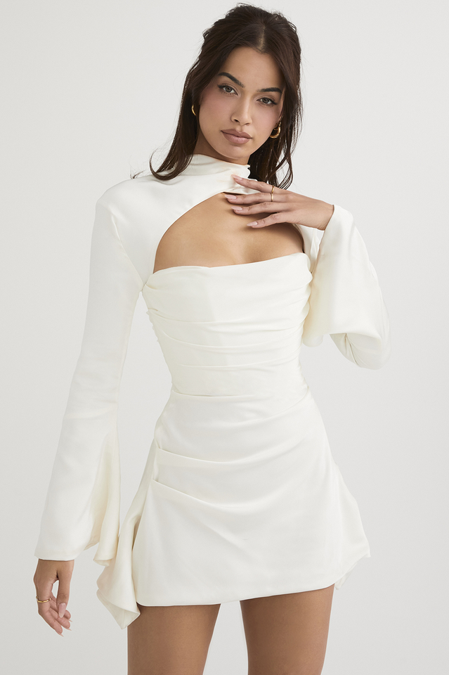 A model poses in a white satin dress with a cutout and flared sleeves.