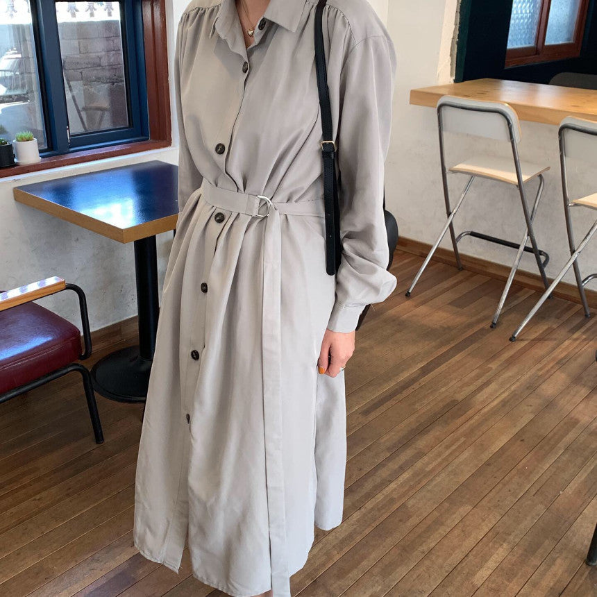 Full shot of a woman in a gray midi dress with a belt and black crossbody bag.