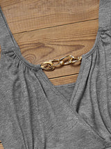 close-up of gold chain detail on the neckline of a gray dress