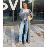 woman wearing a long gray cardigan, white t-shirt, and light blue jeans