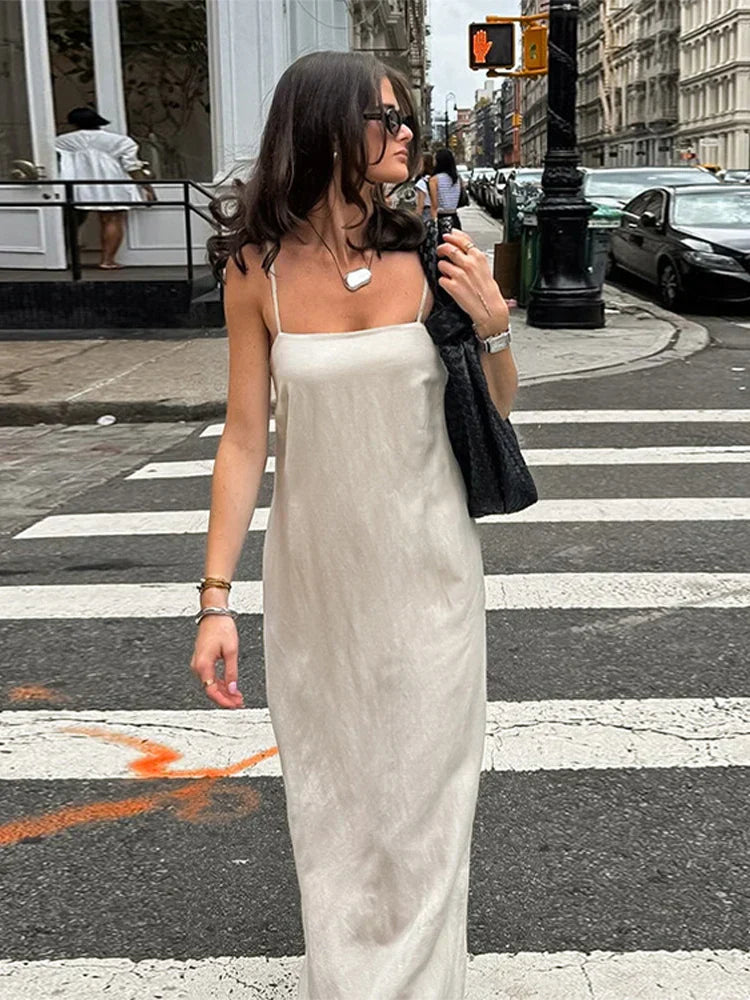 woman in beige slip dress walking on a crosswalk