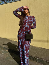 Woman in a floral print maxi dress, shielding her eyes from the sun.