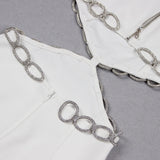 Detail shot of a white dress showing the zipper and silver chain embellishments at the neckline and cut-outs.